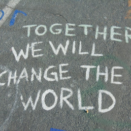 Kreideschriftzug auf einer Straße: Together we will change the world.